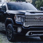 A black 2023 GMC Sierra 2500 HD is shown parked off-road.