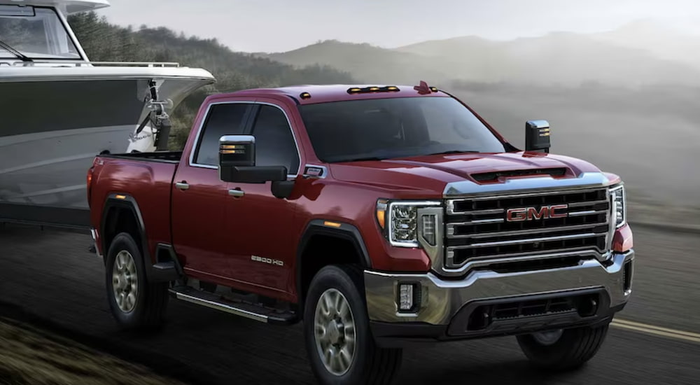 A red 2023 GMC Sierra 2500 HD is shown from the front towing a boat during a 2023 GMC Sierra 2500 HD vs 2023 Chevrolet Silverado 2500 HD comparison.