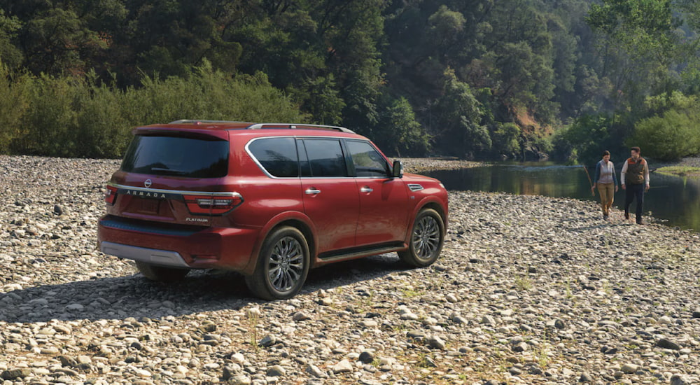 A red 2023 Nissan Armada is shown parked on a beach next to a river.