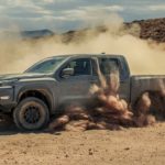 A grey 2023 Nissan Frontier Pro4x is shown off-roading and kicking up dirt.