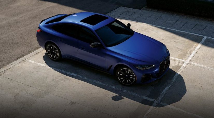 A blue 2023 BMW i4 M50 Gran Coupe is shown parked at a BMW i4 dealer.