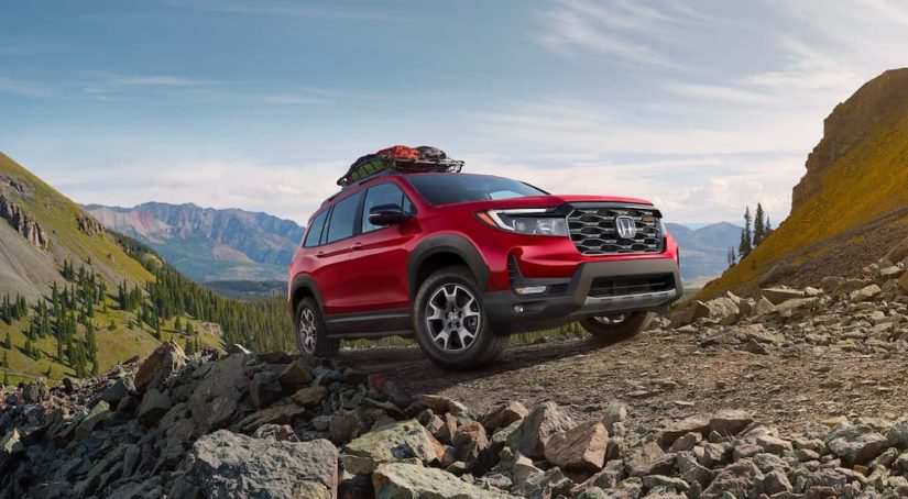 A red 2022 Honda Passport Trailsport is shown on a mountain path after leaving a Certified Pre-Owned Honda dealership.