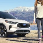 A close up shows a white 2023 Ford Escape Platinum with distant mountains.