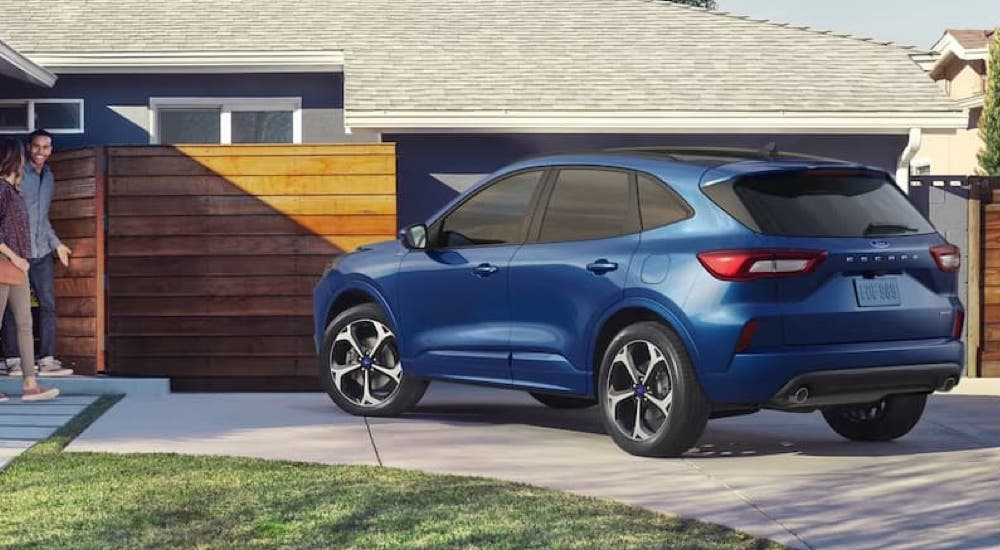 A blue 2023 Ford Escape is shown from a rear angle parked in a driveway.