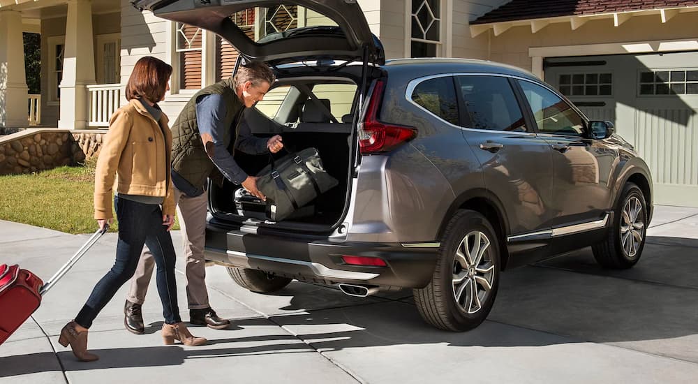 A grey 2022 Honda CR-V Touring is shown being loaded with luggage in a driveway.