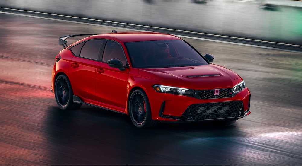 A red 2023 Honda Civic Type R is shown driving on a wet road.