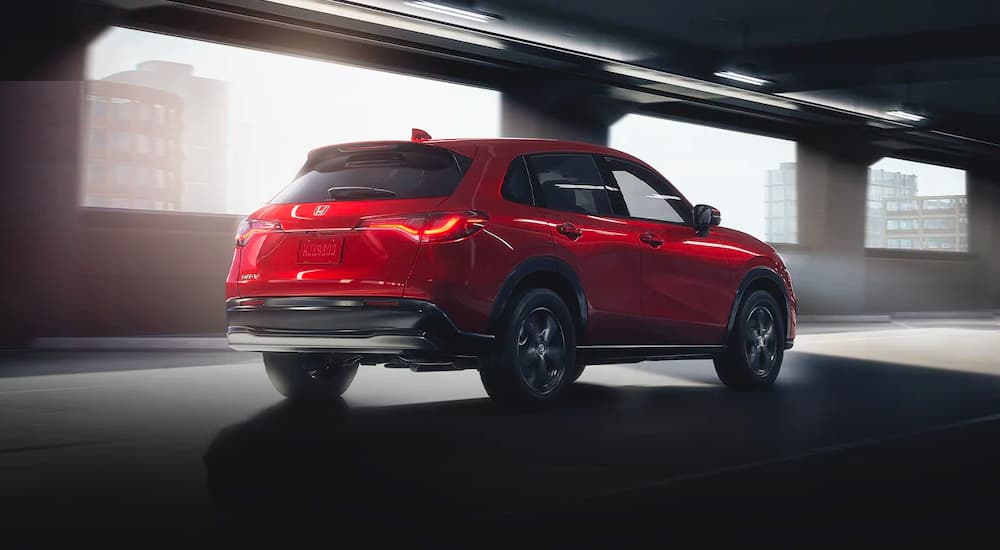 A red 2023 Honda HR-V is shown form the side driving through a tunnel after leaving a Honda dealer.