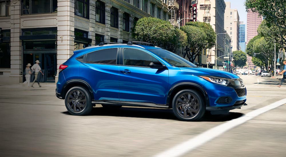 One of the most popular Honda SUVs, a blue 2022 Honda HR-V, is shown driving through a city intersection.