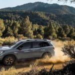 A grey 2023 Honda Passport Trailsport is shown driving on a dusty trail.