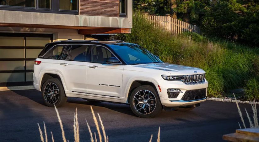 A white 2023 Jeep Grand Cherokee for sale is shown parked in a driveway.