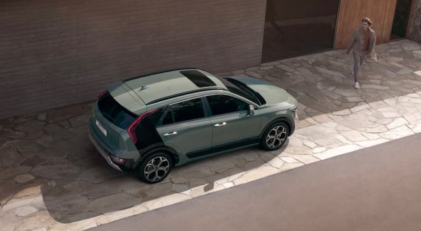 A green 2023 Kia Niro Hybrid is shown from a high angle next to a modern home.