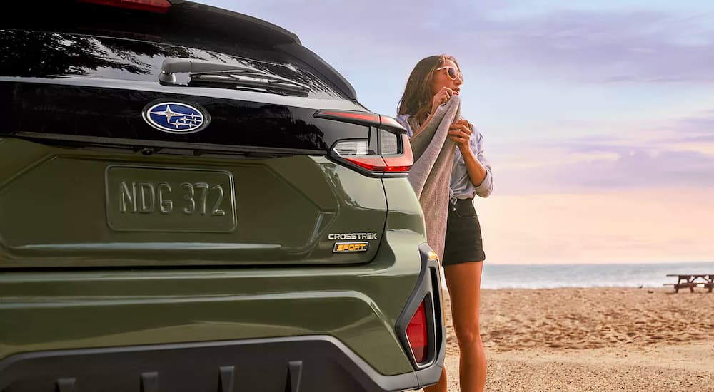 A green 2024 Subaru Crosstrek Sport is shown next to a person with a towel on the beach.