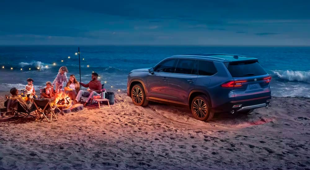 A blue 2024 Toyota Grand Highlander is shown parked on a beach.