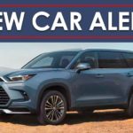 A blue 2024 Toyota Grand Highlander is shown parked on sand under a new car alert banner.