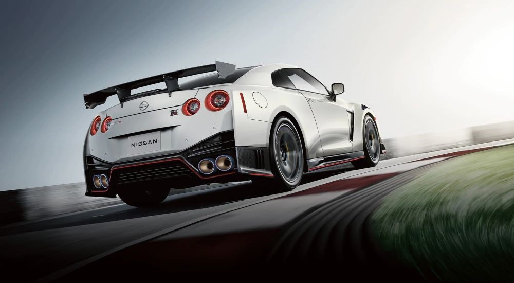 A white 2023 Nissan GT-R Nismo is shown from the rear on a racetrack.