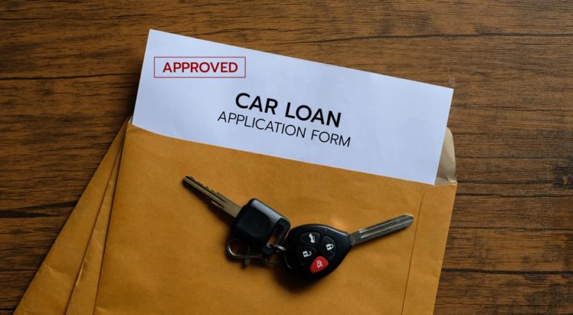 A set of car keys is shown on a manila folder with auto loan information.