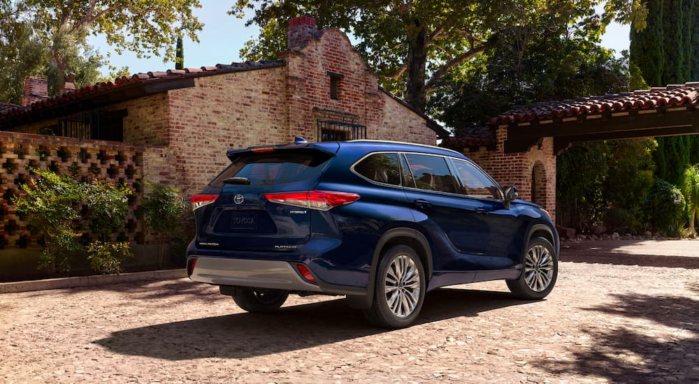 A blue 2023 Toyota Highlander Hybrid Platinum is shown from the rear parked in a driveway.