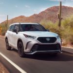 A white 2023 Toyota Highlander XSE is shown driving on a desert road after leaving a Toyota Highlander dealer.