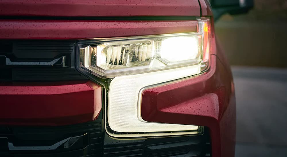 A close up of the headlight on a red 2022 Chevy Silverado 1500 RST is shown.