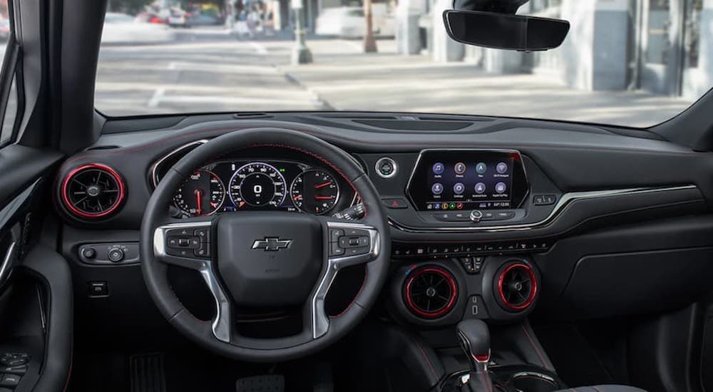 The black interior of a 2019 Chevy Blazer shows the steering wheel and infotainment screen.