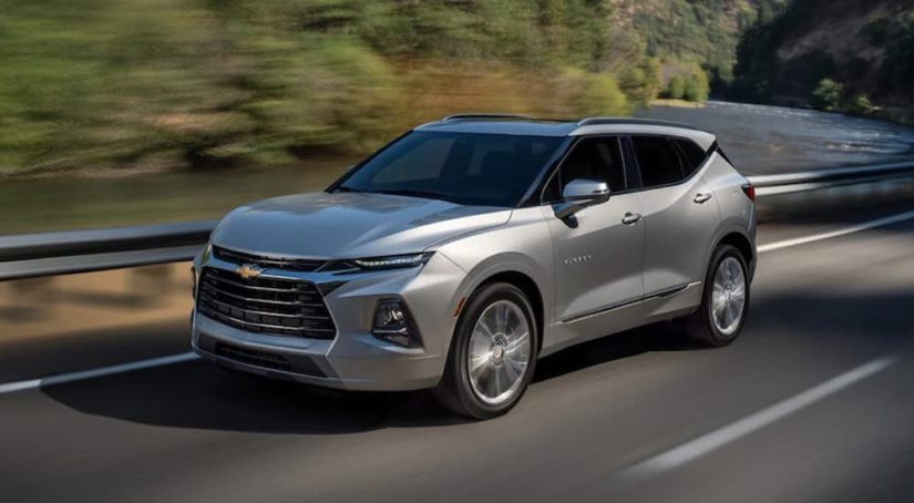 A silver 2021 Chevy Blazer is shown from the side driving on an open road.