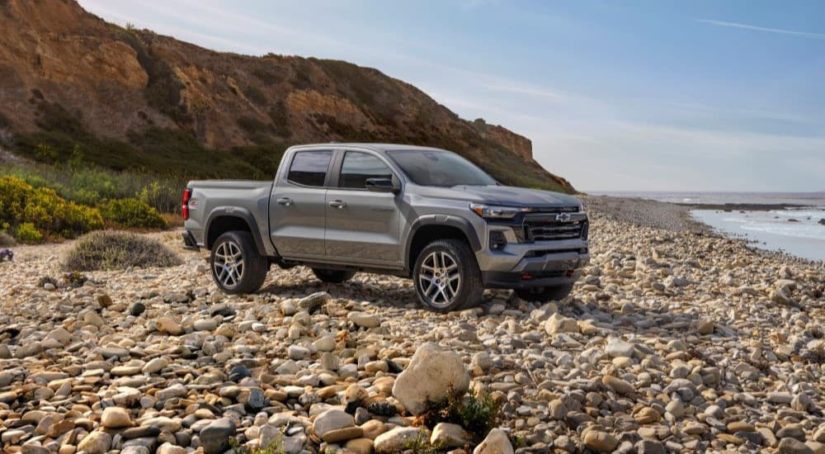 A silver 2023 Chevy Colorado Z71 is shown from the side parked on a rocky beach.