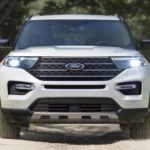 A white 2023 Ford Explorer King Ranch is shown from the front driving on a path.