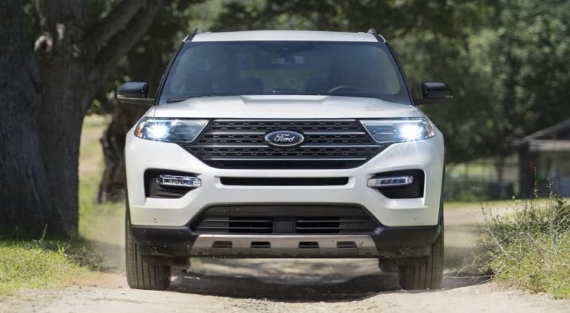 A white 2023 Ford Explorer King Ranch is shown from the front driving on a path.