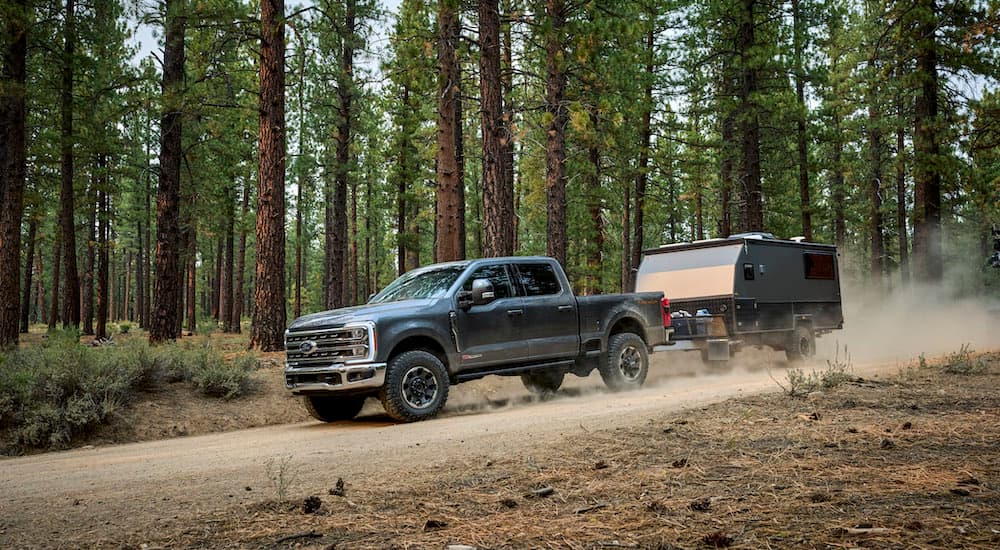 A grey 2023 Ford F-250 Tremor is shown from the side while towing a camper.