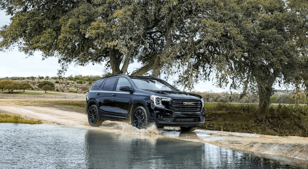 A black 2023 GMC Terrain Elevation is shown driving on a flooded dirt road.