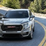 A silver 2023 GMC Terrain SLT is shown driving on a winding road during a 2023 GMC Terrain vs Honda CR-V comparison.
