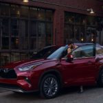A red 2023 Toyota Highlander Hybrid Platinum is shown parked on a city street.