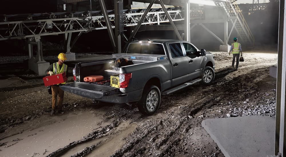 A grey 2023 Nissan Titan XD is shown from the rear at an angle on a jobsite.