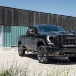 A black 2024 GMC Sierra 2500 HD Denali is shown from the front at an angle during a 2024 GMC Sierra 2500 HD vs 2024 GMC Sierra 3500 HD comparison.