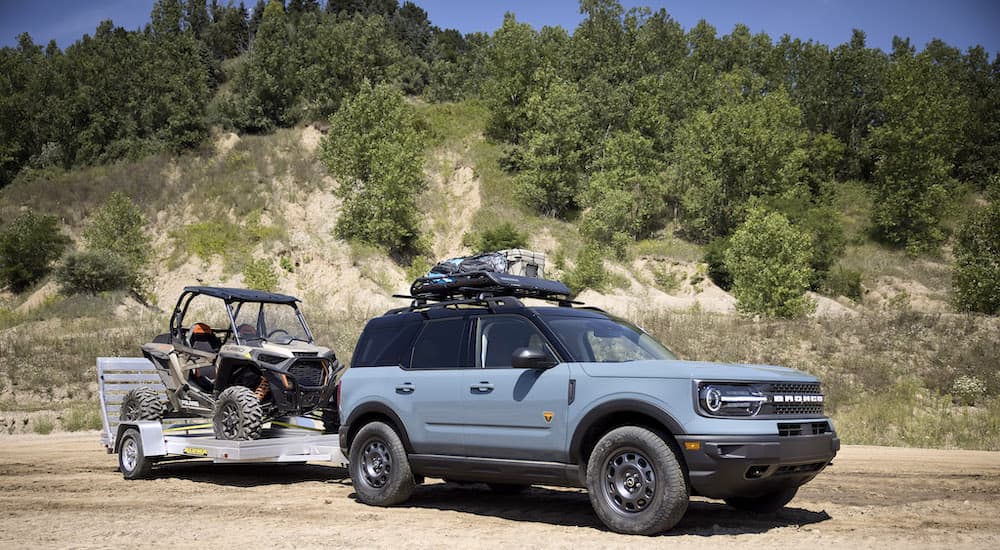 A blue 2023 Ford Bronco Sport is shown from the side while towing a UTV.