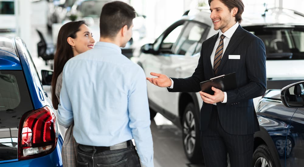 A car salesman is shown speaking to a couple about bad credit car loans.