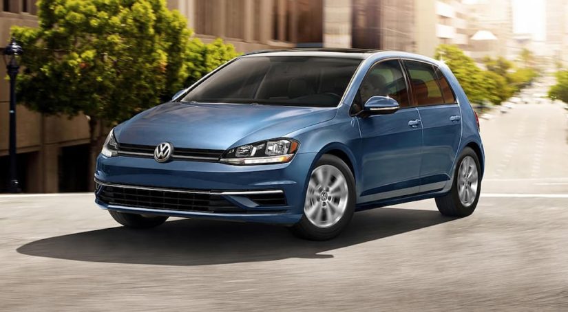 A blue 2021 Volkswagen Golf is shown driving on a city street after leaving a certified VW dealer.