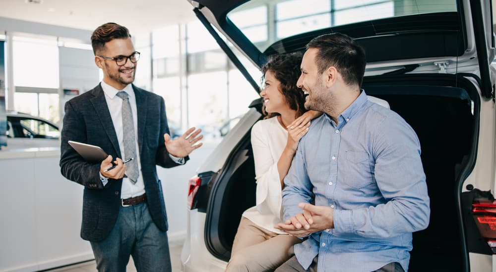 A car salesman is shown speaking to a couple about buying a CPO Volkswagen.