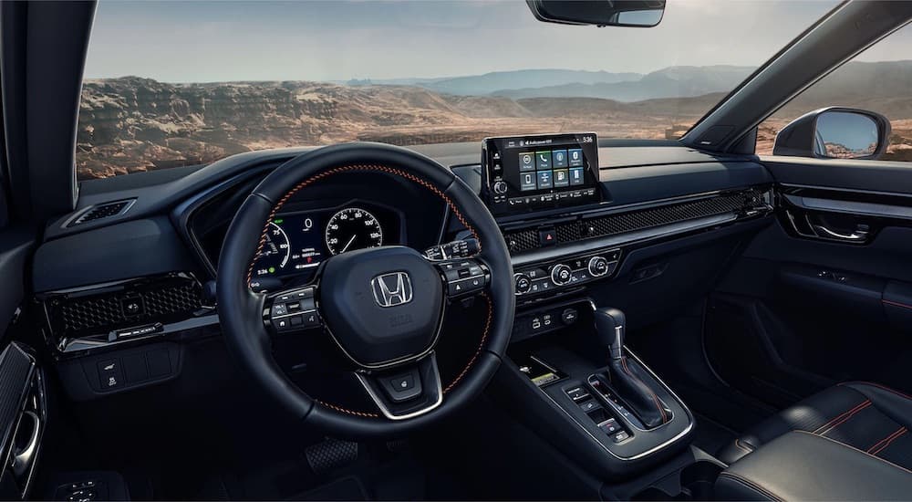 The black interior of a 2023 Honda CR-V is shown from the driver's seat.