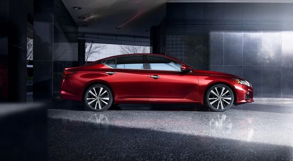 A red 2019 Nissan Altima is shown from the side parked in a modern gallery.