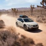 A white 2023 Subaru Crosstrek is shown driving on a dusty trail.