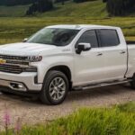 A white 2020 Chevy Silverado 1500 High Country is shown driving on a dirt road.