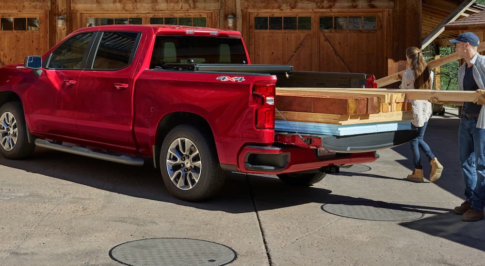 A red 2020 Chevy Silverado 1500 is shown being loaded with construction supplies.