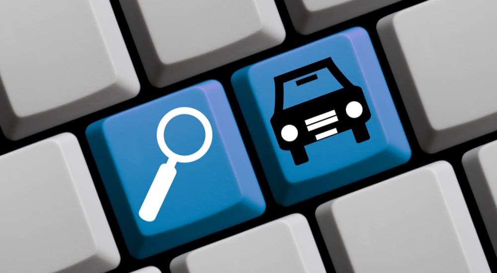 A close up of blue keyboard buttons show a magnifying glass and car icon.