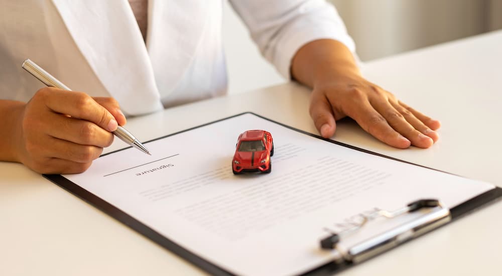 A person is shown filling out paperwork at a dealer.