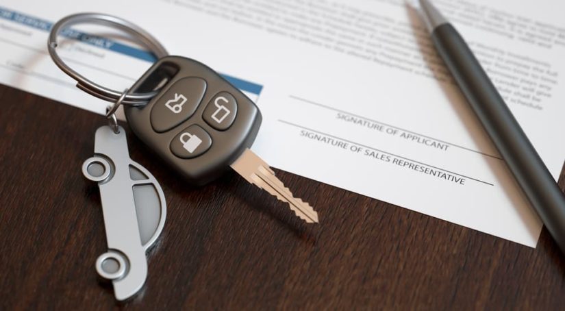 A close up of a car key on paperwork is shown at a car dealership.