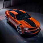 An orange 2023 Chevy Camaro SS is shown parked in a warehouse near a Houston Chevy dealer.