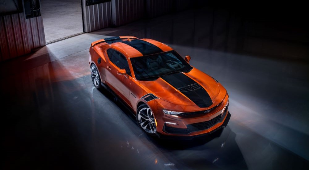An orange 2023 Chevy Camaro SS is shown parked in a warehouse near a Houston Chevy dealer.