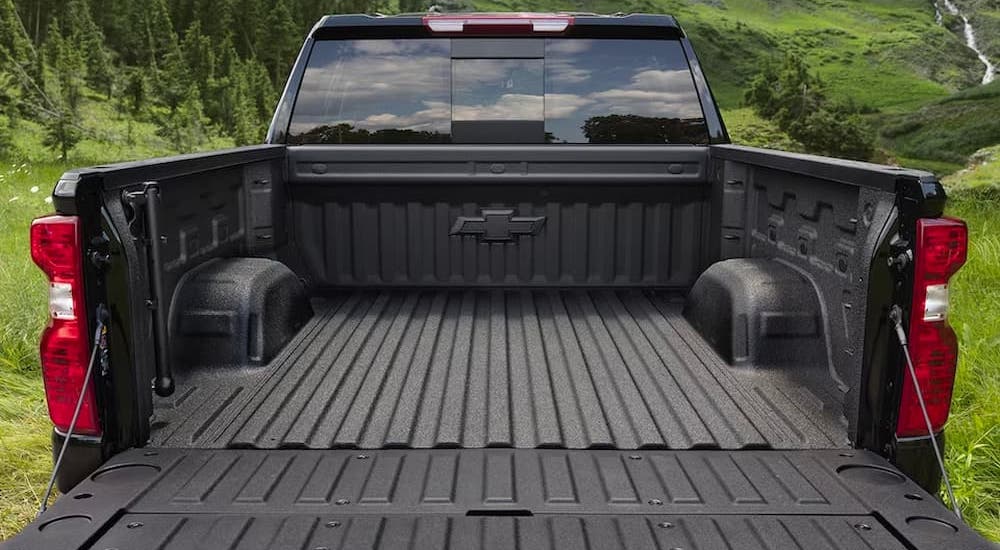 The bed of a black 2023 Chevy Silverado 1500 Custom is shown with an open tailgate.