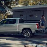 A man and a woman are shown loading a silver 2023 Chevy Silverado 1500 Z71 during a 2023 Chevy Silverado 1500 vs 2023 Ford F-150 comparison.